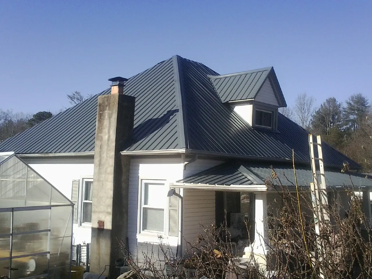 Dark blue standing seam metal roof on a white farmhouse with dormer — Slate & Tile Roof Repair by Roofing Brothers in Macedonia