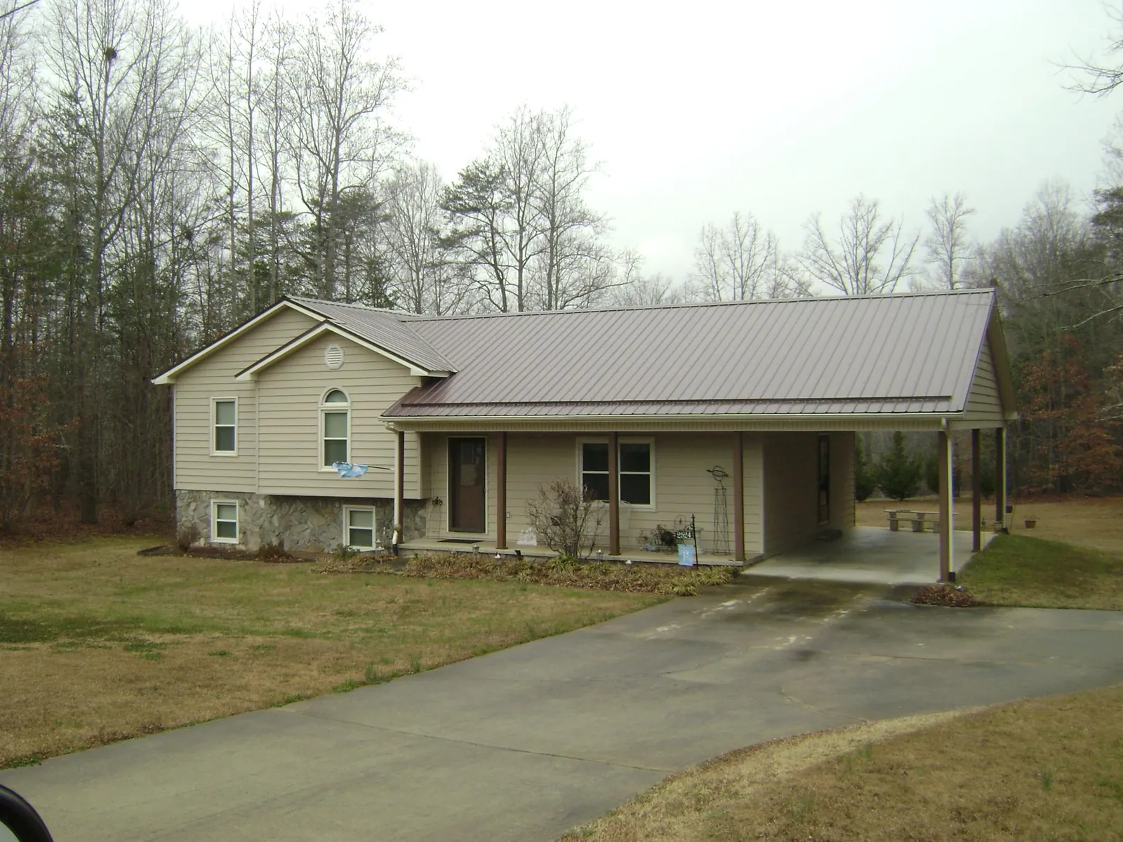 Brown metal roof on a tan split level home with an attached carport in Macedonia