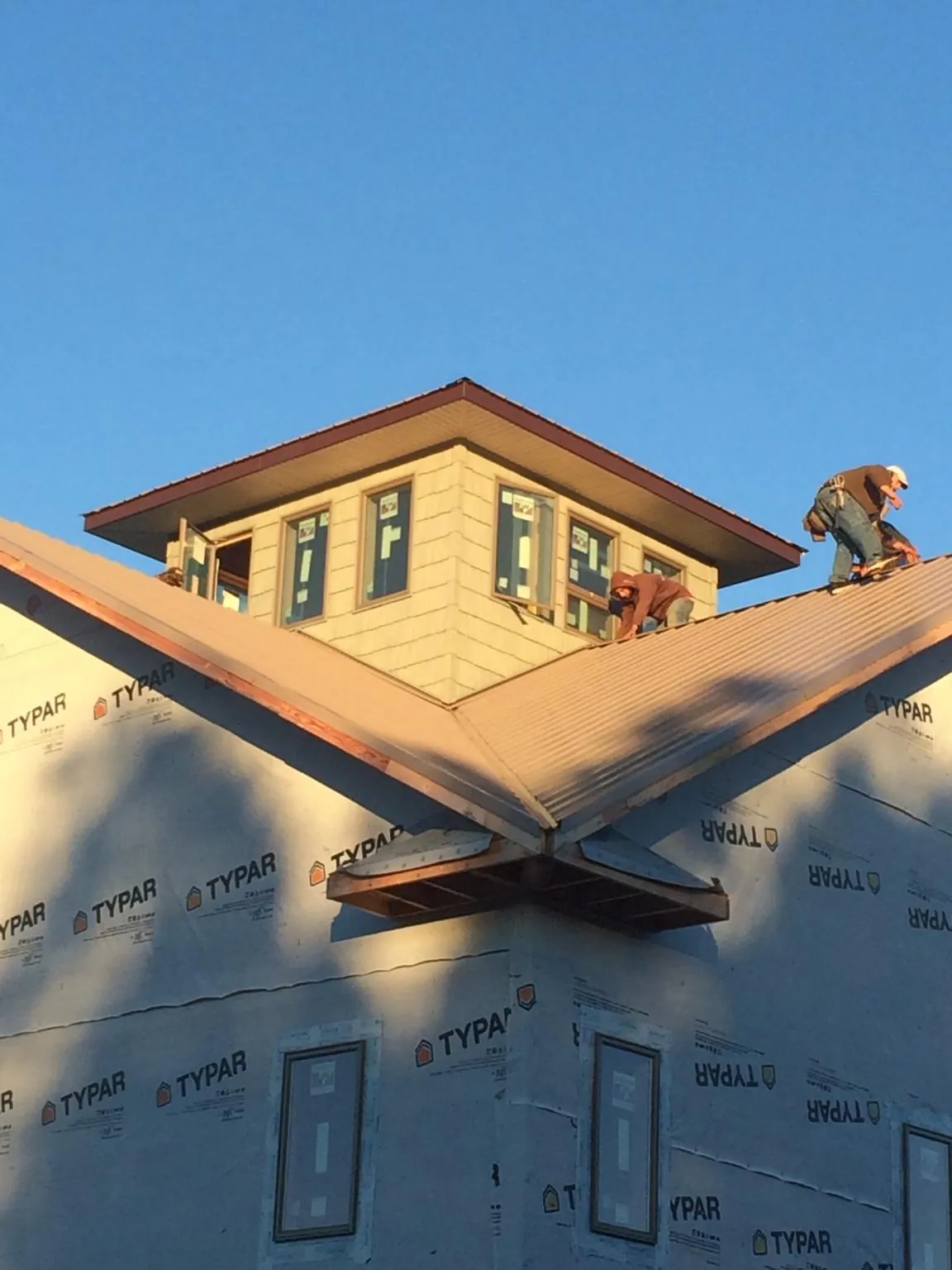 Roofers working around a rooftop cupola on a new metal roof at sunset — Roof Waterproofing in Macedonia by Roofing Brothers